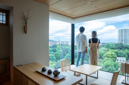 a man and a woman looking out of a large window at ONSEN RYOKAN Yuen Sapporo in Sapporo