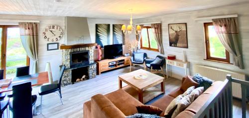 sala de estar con sofá y chimenea en Chalet Ardenne Routy, en Rochehaut