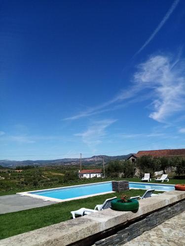 a swimming pool with two lawn chairs next to at Solar dos Avós in Sabrosa