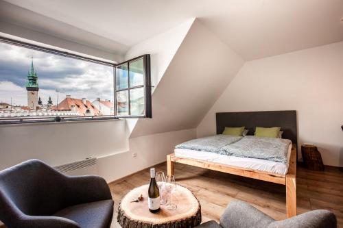 1 Schlafzimmer mit einem Bett, 2 Stühlen und einem Fenster in der Unterkunft Apartmány na Mikulášském náměstí in Znojmo