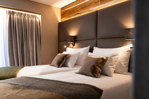 two beds in a hotel room with white pillows at Au Club Alpin in Champex