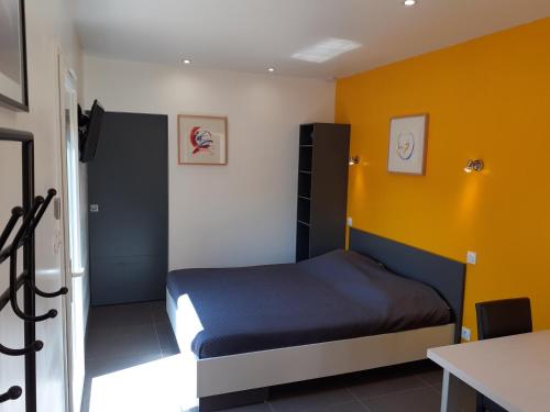 a bedroom with a bed and a yellow wall at Studio les trois chemins in Cucugnan