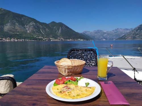 a table with a plate of food and a glass of orange juice at Apartments Babilon in Kotor