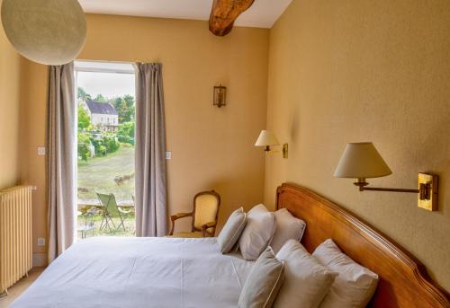 a bedroom with a bed and a large window at Hôtel Restaurant De La Poste & Du Lion D'or in Vézelay