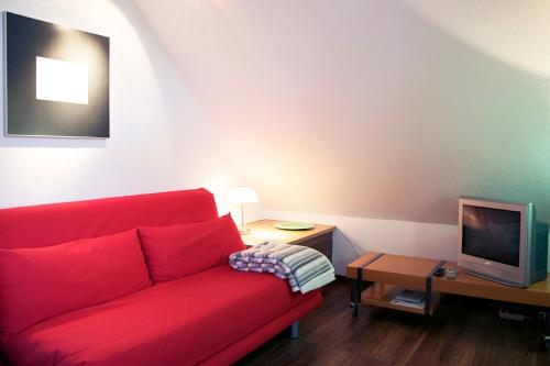 ein Wohnzimmer mit einem roten Sofa und einem TV in der Unterkunft Suite „Niedersachsen“ - wunderschönes Apartment in Fachwerkhaus in Hannover