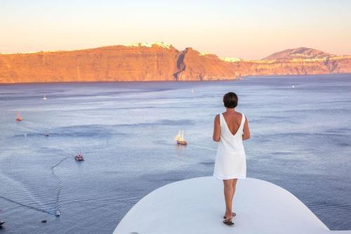 a woman in a white dress looking out over the ocean at Aloia Villas in Oia