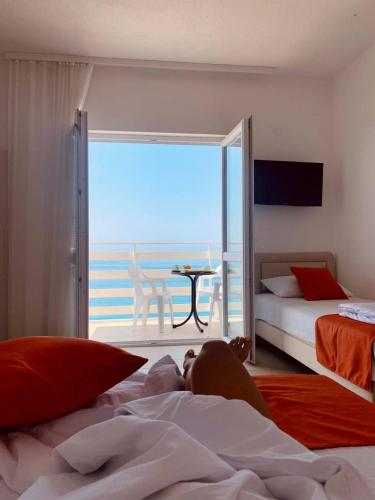 a person laying on a bed in a bedroom with a view at Jelić apartmani in Sutomore