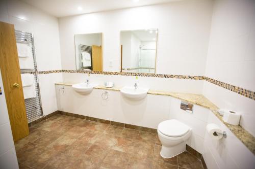 a bathroom with two sinks and a toilet and a mirror at Whitewater Hotel & Spa in Newby Bridge