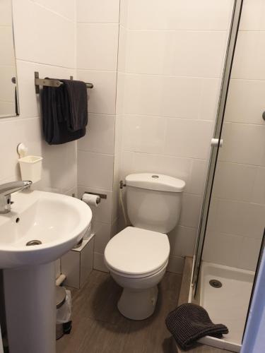 a white bathroom with a toilet and a sink at Hôtel Belfort in Montreuil