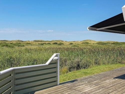 una terraza de madera con un banco en la parte superior de un campo en 6 person holiday home in R m en Lakolk