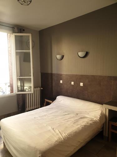 a bed in a bedroom with two lights on the wall at Hôtel Belfort in Montreuil
