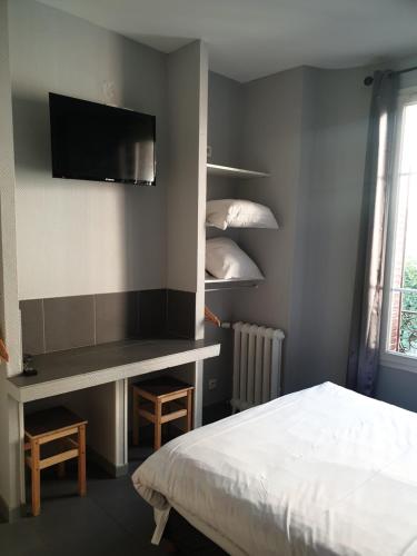 a bedroom with a bed and a desk with a television at Hôtel Belfort in Montreuil