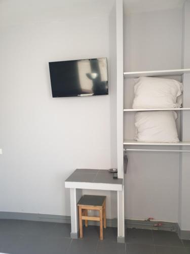 a room with a table and a tv on a wall at Hôtel Belfort in Montreuil