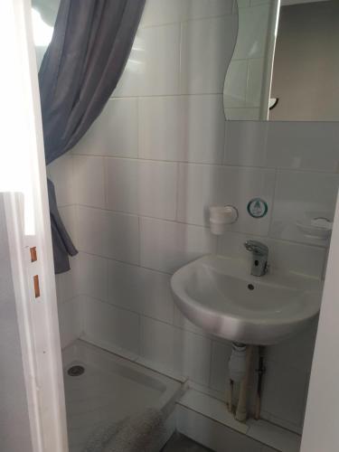 a white bathroom with a sink and a mirror at Hôtel Belfort in Montreuil