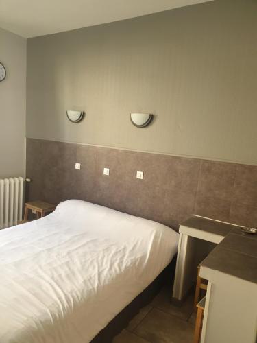 a bedroom with a bed and two lights on the wall at Hôtel Belfort in Montreuil