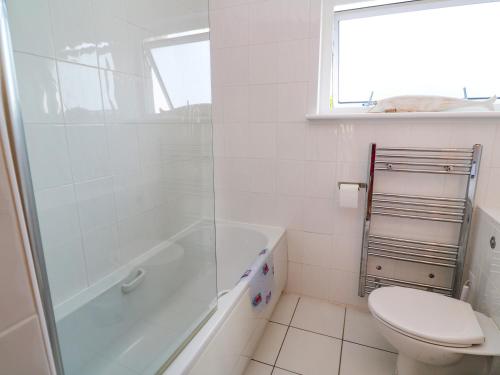 a white bathroom with a shower and a toilet at The Poop Deck in Helston