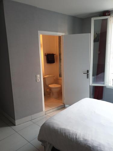 a bedroom with a bed and a bathroom with a toilet at Hôtel Belfort in Montreuil