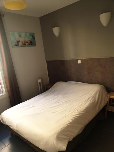 a bedroom with a white bed in a room at Hôtel Belfort in Montreuil
