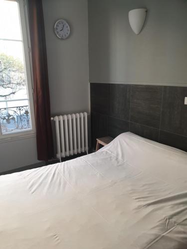a bedroom with a bed and a clock on the wall at Hôtel Belfort in Montreuil