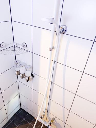 a shower in a bathroom with white tiles at Otohaya Guesthouse in Nagoya
