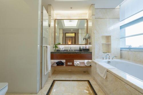 bagno con vasca e grande specchio di Ordos Yonggui Hotel a Ordos