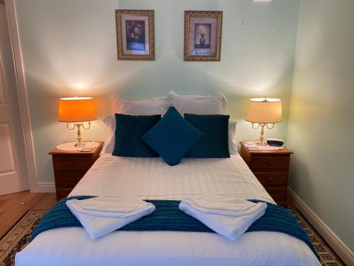 a bedroom with a bed with blue pillows and two lamps at Curtis Falls Studio-Apartment in Mount Tamborine