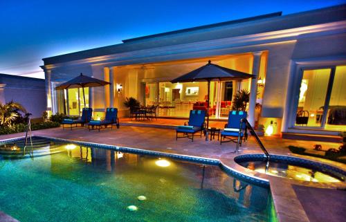 a house with a swimming pool with chairs and umbrellas at Pueblo Bonito Emerald Luxury Villas & Spa All Inclusive in Mazatlán