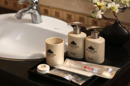 a bathroom sink with three toiletries on a table at ĐỨC TRỌNG HOTEL in Hanoi