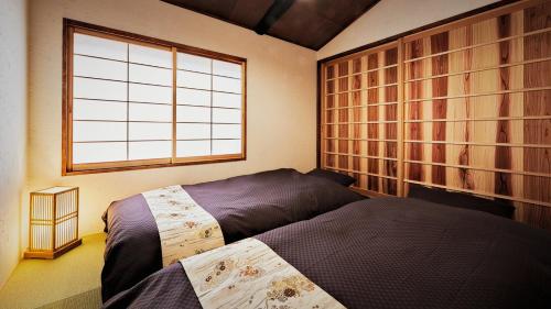 1 Schlafzimmer mit 2 Betten und einem Fenster in der Unterkunft Kokonoe Machiya in Kyoto