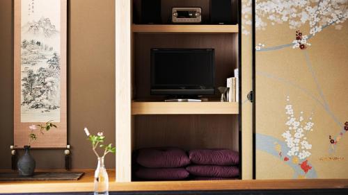 a cabinet with a tv in it with purple cushions at Kokonoe Machiya in Kyoto