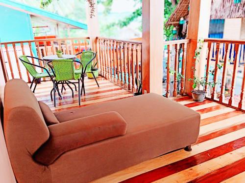 a brown couch sitting on a porch with a table and chairs at SmallFry's Beach Resort in Calatrava
