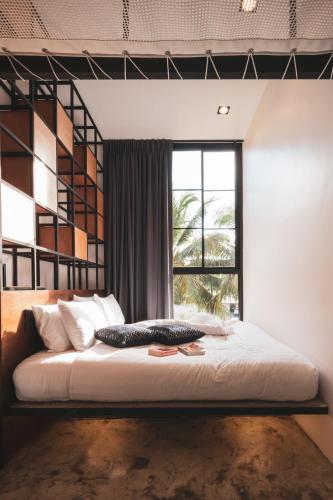 a bedroom with a large bed with a window at Book a Bed Poshtel - SHA Plus in Phuket Town