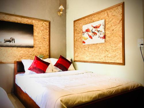 a bedroom with a bed with red and white pillows at Saming Chiang Dao Guest House in Chiang Dao