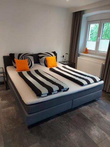 a large bed with orange and black pillows on it at Landhaus Goldenes Kreuz in Leutkirch im Allgäu