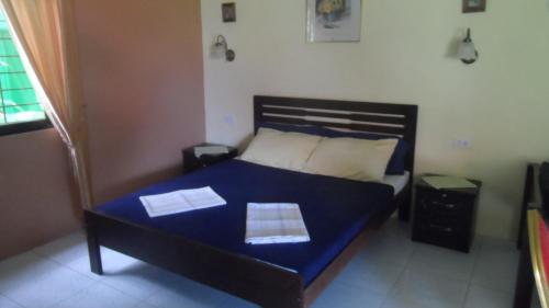 a bedroom with a bed with blue sheets and two papers on it at Bungalow auf Sibuyan am Strand nahe Cresta de Gallo in Azagra