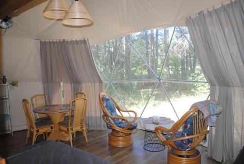 a room with a table and chairs and a large window at Glamping Drzwi Do Lasu in Supraśl