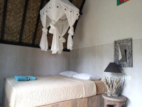 a bedroom with a bed with curtains and a lamp at Zelobi Omnivora Cottage in Kintamani