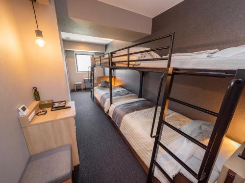a dorm room with three bunk beds and a desk at Super Hotel Premier Kanazawaeki Higashiguchi in Kanazawa