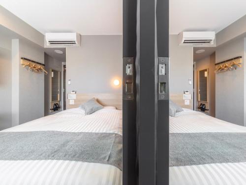 two beds in a bedroom with two mirrors at Super Hotel Premier Kanazawaeki Higashiguchi in Kanazawa