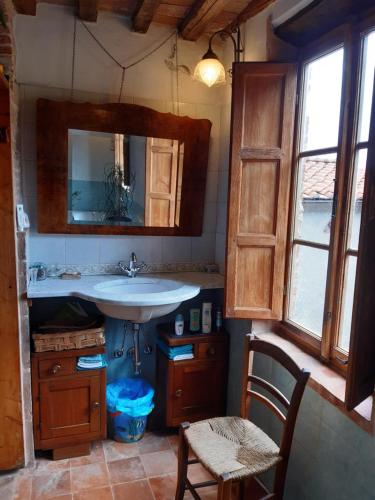 baño con lavabo, espejo y silla en Attic with balcony at Locanda del Capo, en Capannori