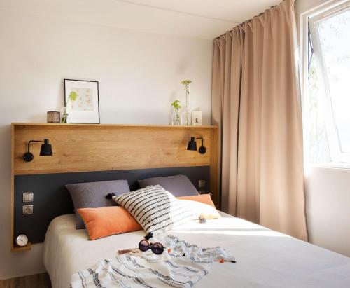 a bedroom with a bed with white sheets and orange pillows at Camping les vergers de Squividan *** in Tréffiagat