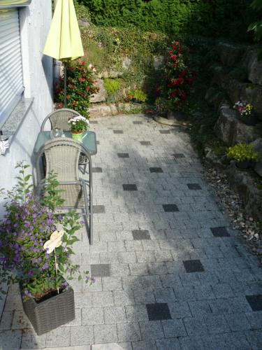 a patio with a table and a chair and flowers at Gästezimmer in Aspach in Aspach