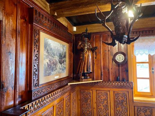 a room with wooden walls and a clock and a statue at Penzion Rejviz in Rejvíz