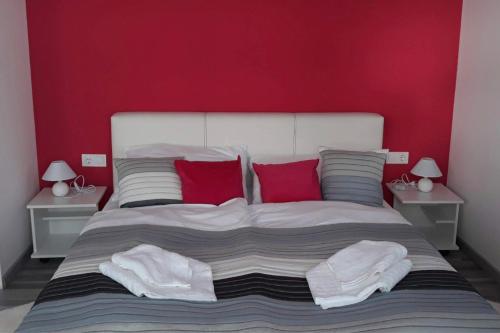 a bedroom with a large bed with red walls at Gabriella Panzió in Bük