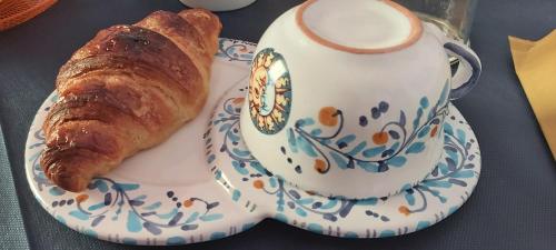 a plate with a cup of coffee and a croissant at B&B SoleLuna della Solidarietà in Palermo