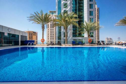 a large swimming pool with palm trees and buildings at Great Location 1BR Botanica Dubai Marina in Dubai