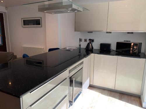 cocina con armarios blancos y encimera negra en Mitre Court Holiday Home en Plymouth