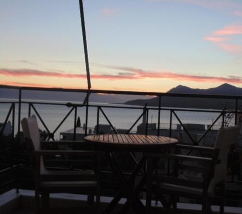 a table and chairs on a balcony with the sunset at Nefeli Studios in Loutra Edipsou