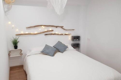 a bedroom with a white bed with lights on it at Amb encant i estil Mediterrani en zona tranquilla de Llançà i amb terrassa in Llança