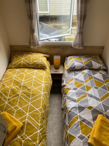 two beds in a small room with a window at Haggerston Castle 6 Berth Caravan - Riverside 37 in Cheswick